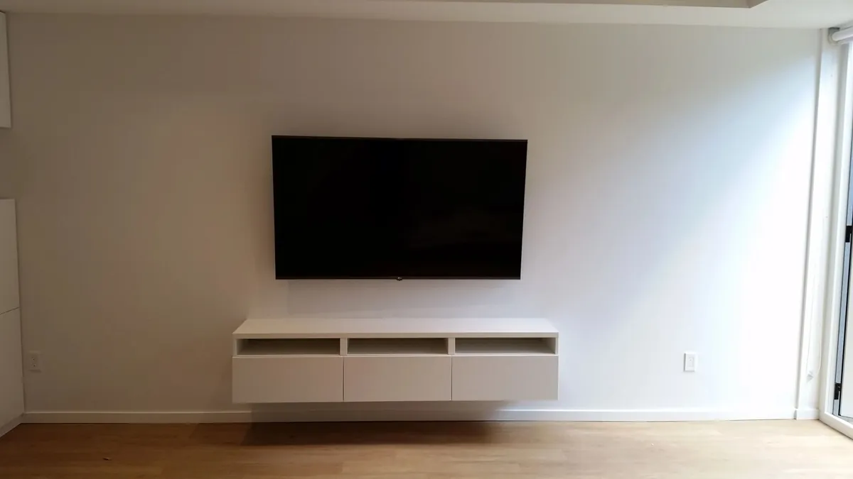 TV mounted above a floating console in a finished room