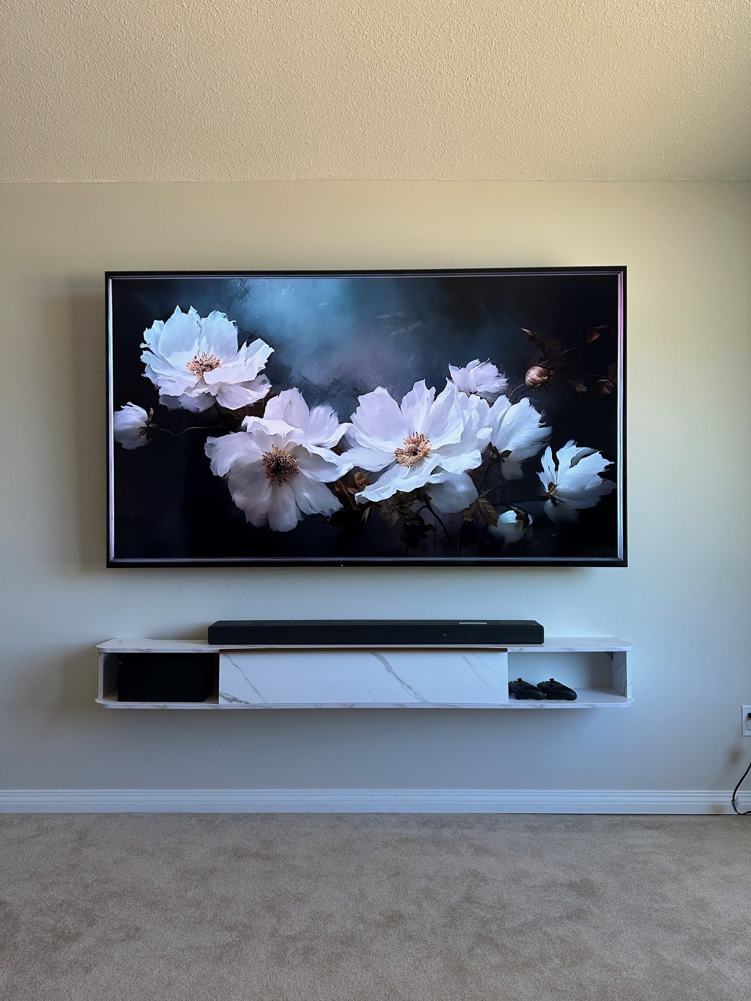 Soundbar mounted on the wall directly beneath a Frame TV above a floating console
