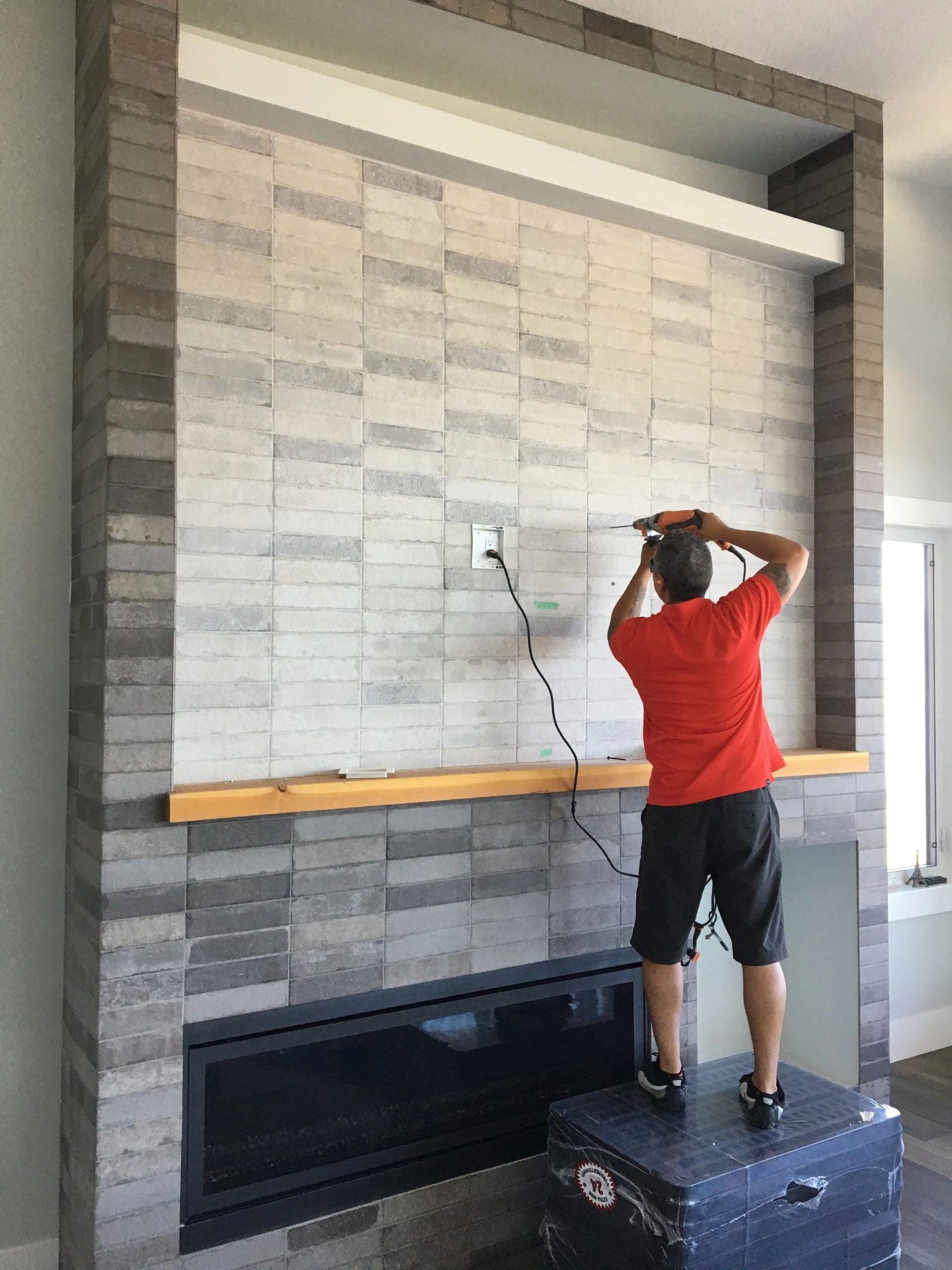 Wil Martinez installing a TV mount on a stone feature wall